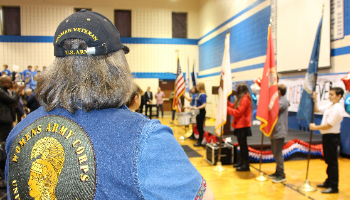 Woman veteran watches students holding flags