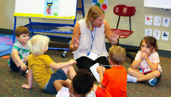 a teacher sits on floor with children